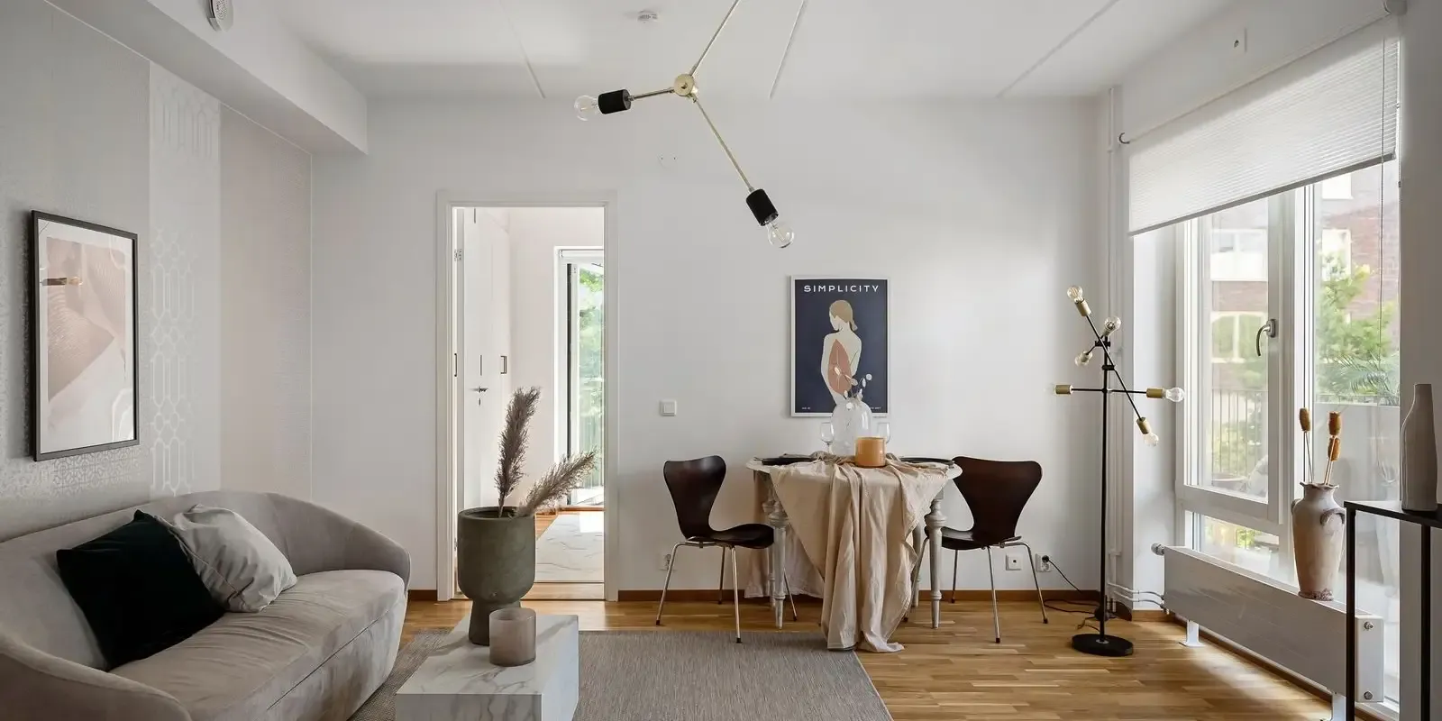 Salón luminoso con sofá, mesa de comedor y ventanal